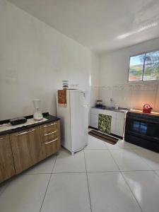 a white kitchen with a refrigerator and a stove at Ap Aconchego Carapitangui in Barra Grande