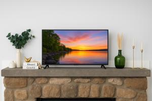a tv on a fireplace with a sunset at Modern Lakeview Escape | Scenic Deck • Fire Pit in Monroe