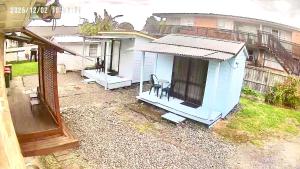 a small blue house with a chair in a yard at A Cozy Cabin for two in Hamilton East near to CBD and Waikato Hospital in Hamilton