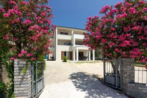 a gate with pink flowers in front of a building at Apartmani Ljubica in Duće