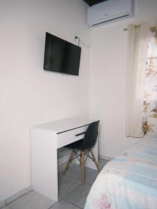 una scrivania con una TV su una parete accanto a un letto di Hotel e Churrascaria Major a Major