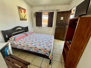Un dormitorio con una cama, una mesa y un televisor. en Pousada Jirê, en Itacaré