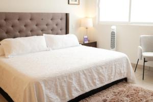 a bedroom with a white bed with a large headboard at Providencia Amealco in Amealco