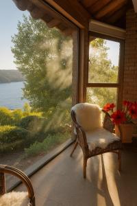 a chair sitting in front of a window with a view at Beachfront house for 20 people in Vichuquén Lake