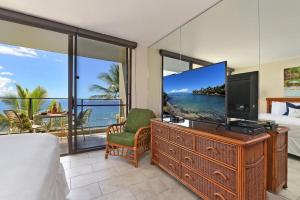 a bedroom with a large screen tv and a bed at Mahana 602 · MA 602 Kaanapali OceanFront Studio Ocean View Pool in Kahana