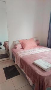 a bedroom with a bed with pink sheets and a mirror at Apartamento 2 quartos Serra in Serra +9 photos