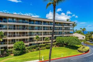 an apartment building with a palm tree in front of it at Maui Banyan P301 · MB P301 Remodeled 2BD Condo Across Beach Pool in Wailea