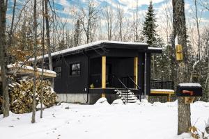 a black cabin in the woods in the snow at Le 4 sur le lac, Accès au lac, Boisée, BBQ in Wentworth