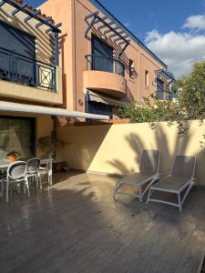 two chairs and tables on a patio in front of a building at Gurugu Beach House in Palm-Mar