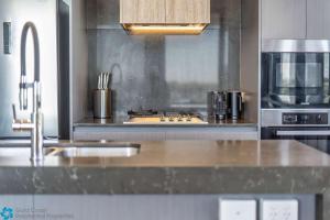 a kitchen with a stove top oven next to a microwave at Ocean View 3 Bedroom with Great Facilities in Gold Coast +18 photos