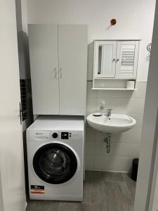 un piccolo bagno con lavatrice e lavandino di 1 Zimmer Häuschen a Itzehoe