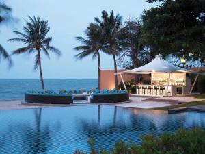 a swimming pool with a tent and palm trees and the ocean at Mövenpick Asara Resort & Spa Hua Hin in Hua Hin +157 photos