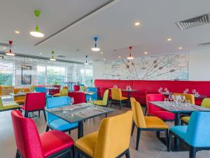 a restaurant with colorful tables and chairs and a map at Ibis Styles Bucharest Airport in Otopeni