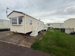una casa pequeña estacionada en un patio con porche en JTD golden gate caravan park towyn hire, en Kinmel Bay