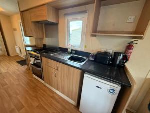 Una pequeña cocina con fregadero y estufa. en JTD golden gate caravan park towyn hire, en Kinmel Bay 6 fotos más