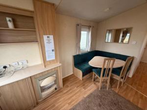 un pequeño comedor con mesa y chimenea en JTD golden gate caravan park towyn hire, en Kinmel Bay