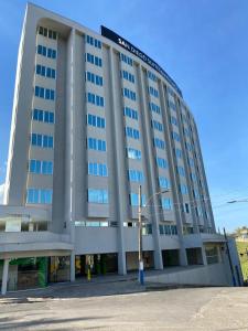 Un gran edificio blanco con un cartel en él. en San Diego Suítes Manhuaçu, en Manhuaçu