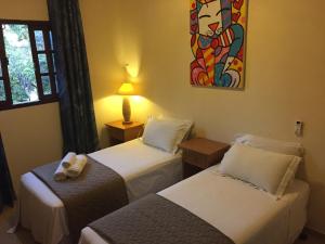 a room with two beds and a painting on the wall at CostaSol Pipa Chalés in Pipa