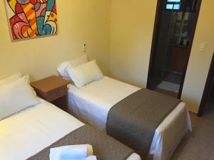 a hotel room with two beds and a window at CostaSol Pipa Chalés in Pipa