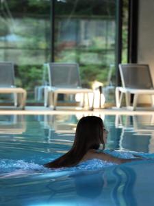 スキュネイザにあるPhoenix Medical Resortの椅子付きスイミングプールでの女性の水泳