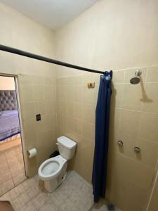 a bathroom with a toilet and a blue shower curtain at Casa de los Abuelos in Itzamatitlán +13 photos
