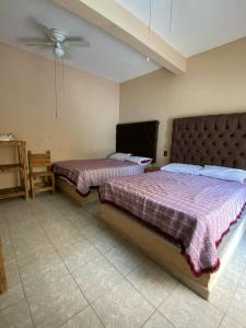 sypialnia z dwoma łóżkami i wentylatorem sufitowym w obiekcie Casa de los Abuelos w mieście Itzamatitlán
