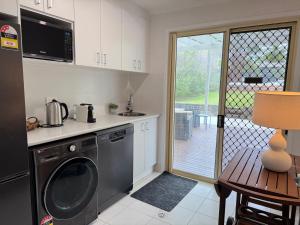 a kitchen with a washing machine and a table and a door at Palacete Beach Resort - entire home in Culburra Beach