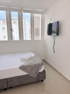 Habitación blanca con cama y TV de pantalla plana. en hotel portal del cerro manizalez, en Manizales
