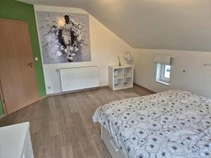 ein Schlafzimmer mit einem Bett und einem Gemälde an der Wand in der Unterkunft Chambre proche du circuit in Spa