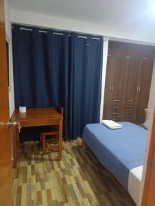 ein Schlafzimmer mit einem Bett und einem Schreibtisch mit einem blauen Vorhang in der Unterkunft Departamento Frente al Cc Mega plaza - Ica in Ica + 3 Fotos