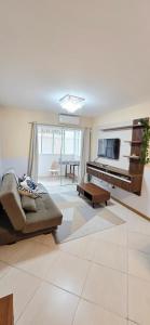 ein Wohnzimmer mit Sofa und Fernseher in der Unterkunft Jardim das Américas in Bombinhas