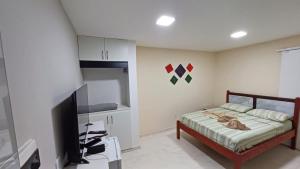 una camera da letto con un letto e una TV a schermo piatto di Suíte península de Búzios a Búzios