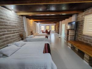 a row of four beds in a room at Casa de Sal - Salt Hotel in Uyuni