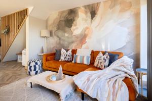 a living room with an orange couch and a painting at Luxury Stay, City Walk, Pool Table & Air Hockey, Garden, Parking, Business & Families - Oakview in Colchester