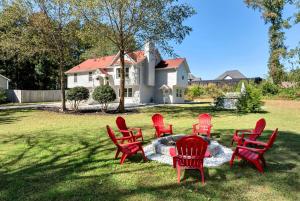 Un grupo de sillas rojas colocadas en el césped frente a una casa. en Spacious 5BR Family Retreat Near Mall of GA Sleeps 13, en Buford