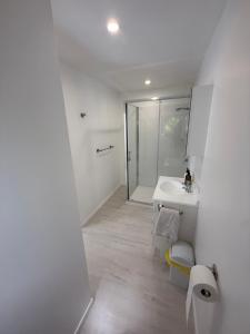 a white bathroom with a shower and a sink at Whangapoua retreat in Whangapoua +27 photos