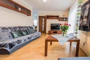 a living room with a couch and a table with flowers at Apartamenty Izerskie - ul. Cicha 13F-G in Świeradów-Zdrój