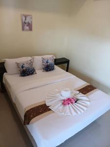 Una cama blanca con una vela y una flor encima. en ไลอ้อน โฮเทล, en Chumphon