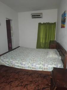 a bed in a bedroom with a green curtain at Casa a 10 minutos de la playa y 15 del aeropuerto in Catia La Mar