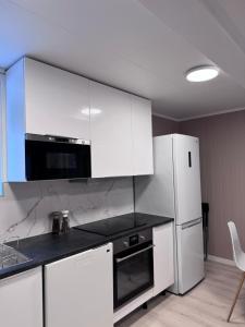 a kitchen with white cabinets and a white refrigerator at Kirkevegen apartment in Brumunddalen +16 photos