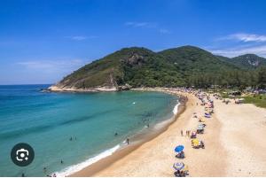a beach with a bunch of people in the water at Refúgio de luxo in Pedra de Guaratiba