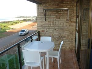a balcony with a white table and chairs and a car at Blue Horizon Flat 8 in Jeffreys Bay +9 photos
