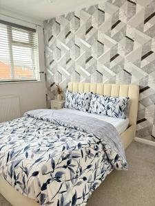 ein Schlafzimmer mit einem Bett und einer geometrischen Akzentwand in der Unterkunft Wigan 2-Bedroom Modern house - Cozy & Relaxing Stay in Bickershaw