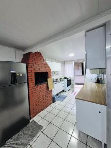 una cucina con muro di mattoni e una cucina con frigorifero di Cabana Amarela Guarda do Embaú a Palhoça Altre 15 foto