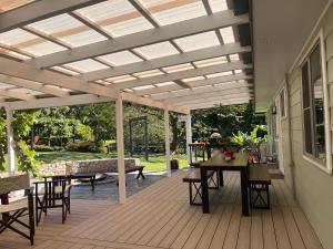a pergola on a deck with a table and chairs at Cedarvale Cottage in Boambee