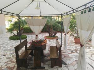 un patio con tavolo e sedie sotto una tenda. di Villalba a Castellammare del Golfo