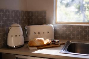 克莱尔Donnybrook Cottages - Hutt River的厨房柜台配有烤面包机和切板上的面包