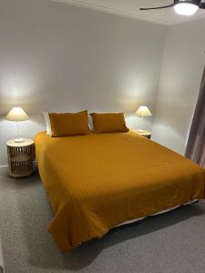 a bedroom with a large yellow bed with two lamps at Spacious 3 bdrm Unit, Rocky CBD in Rockhampton