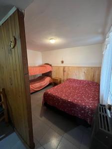 una camera con 2 letti e un copriletto rosso di Piltri2 monoambiente a El Bolsón