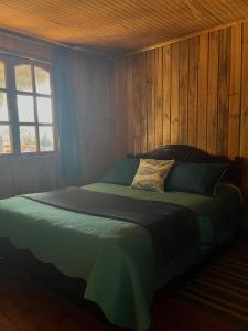 ein Schlafzimmer mit einem Bett mit einer Holzwand in der Unterkunft Cabaña AlbaMarina - Pichilemu in Pichilemu